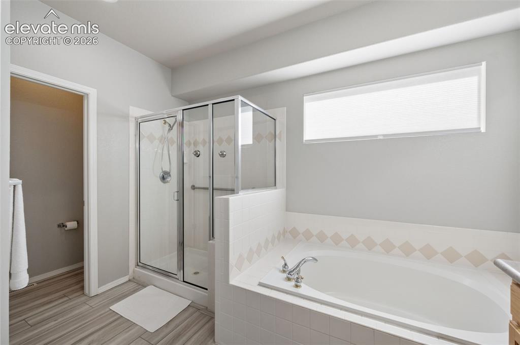 Image 16 of 37: Bathroom featuring a glass-enclosed shower, a tiled soaking tub with a deck