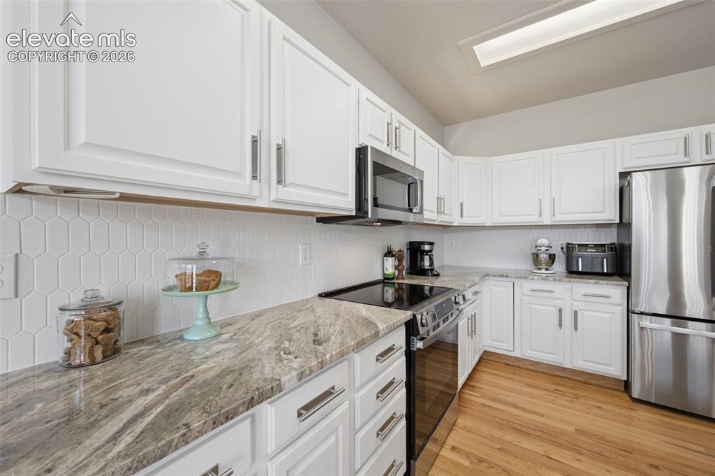 Image 20 of 37: Kitchen featuring white cabinetry, stone-patterned countertops, a white hex