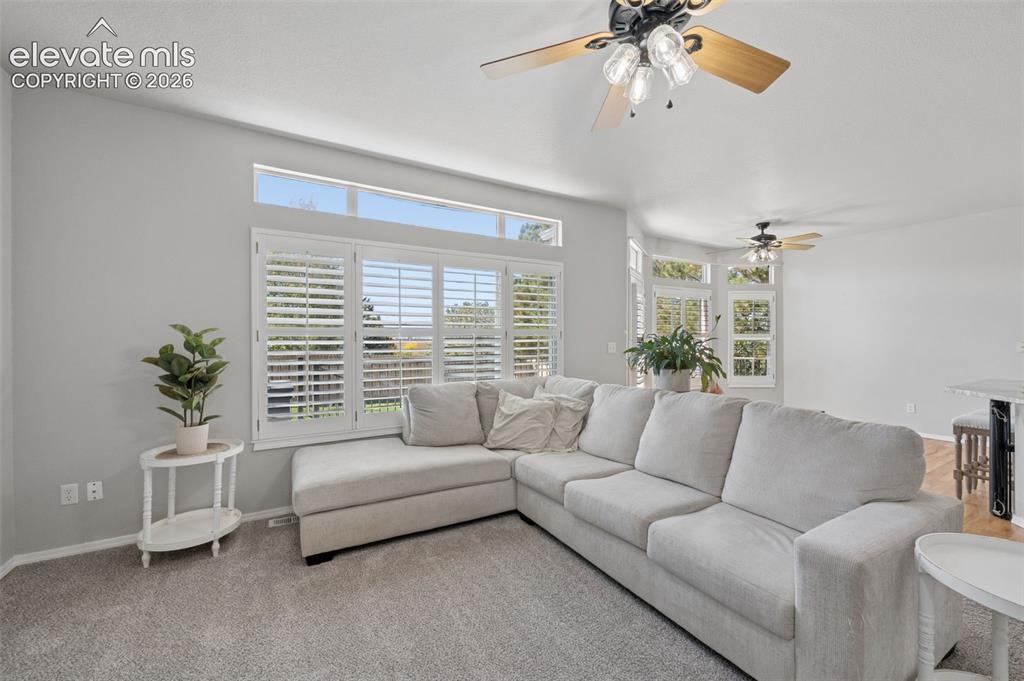 Image 27 of 37: Living area featuring tiered transom windows, plantation shutters, and ceil