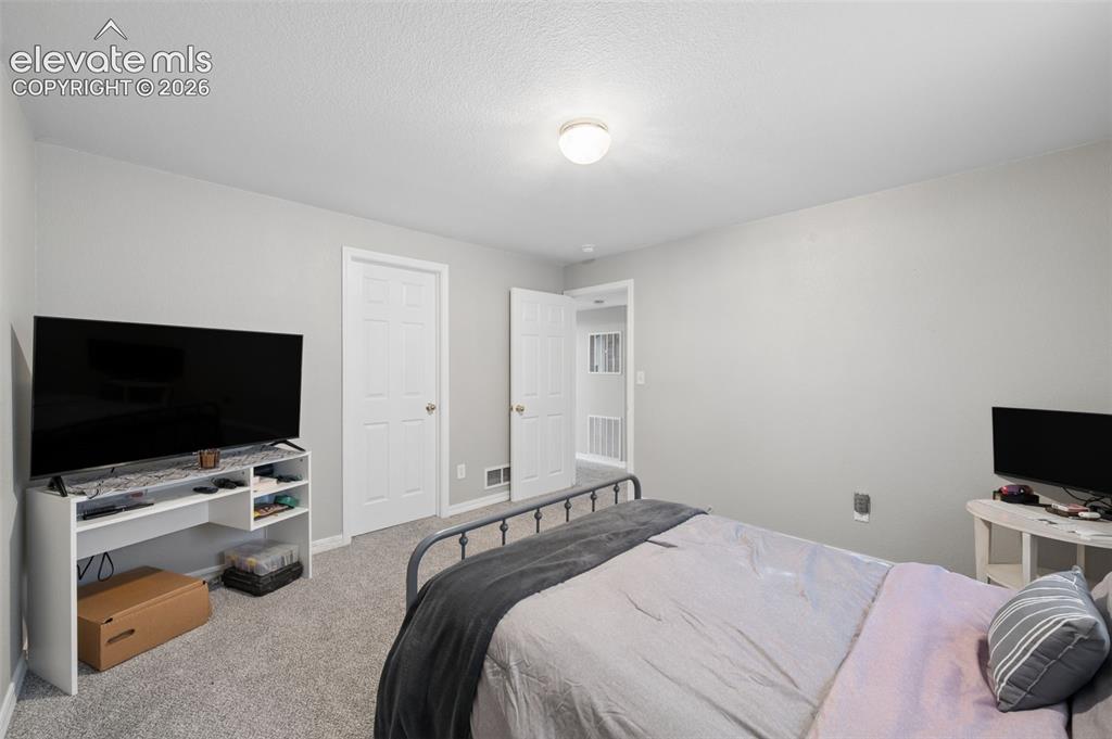 Image 32 of 37: Neutral wall palette with two-panel interior doors, plush carpeting, and a 