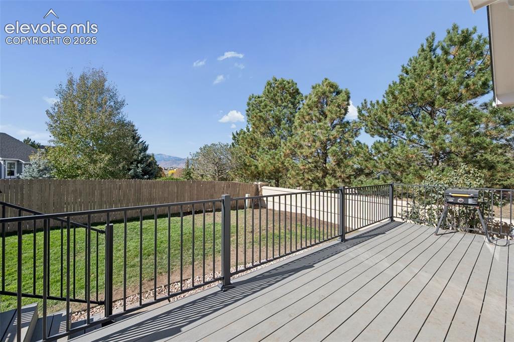 Image 34 of 37: Elevated composite deck featuring a black metal railing, manicured lawn, pe
