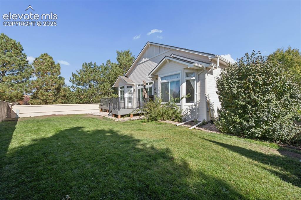 Image 35 of 37: Backyard featuring a manicured lawn, elevated deck with iron railing, light