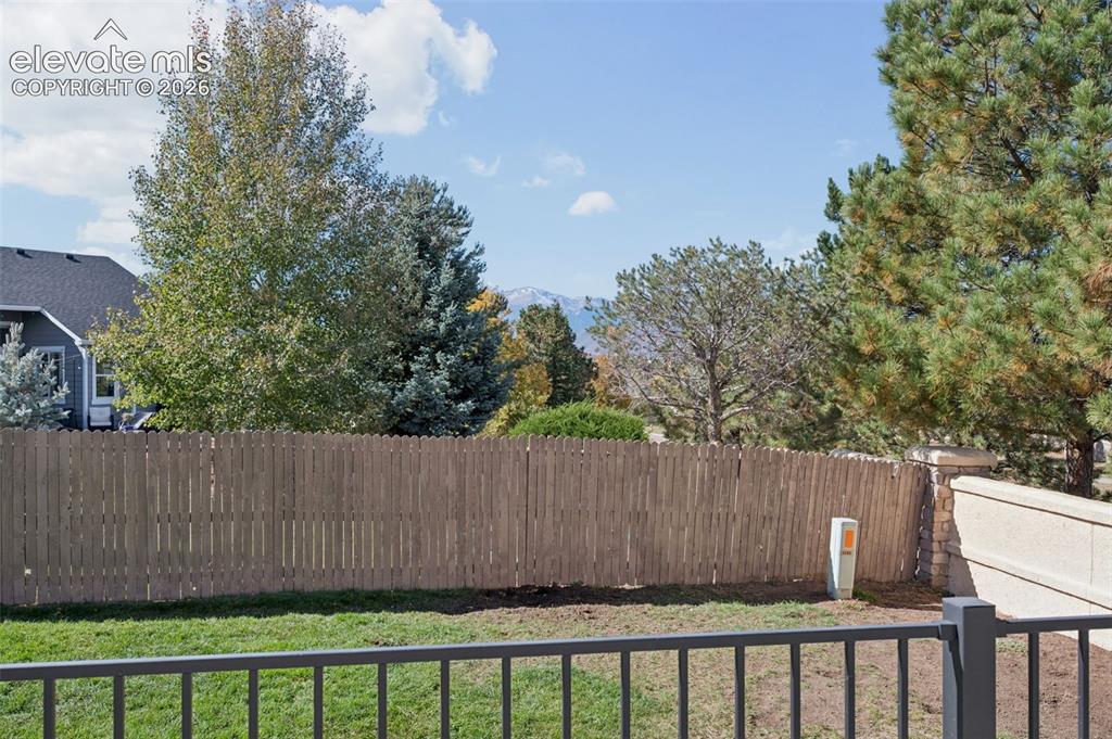 Image 37 of 37: Backyard featuring a grass lawn, metal fencing, wood-slat privacy fencing,
