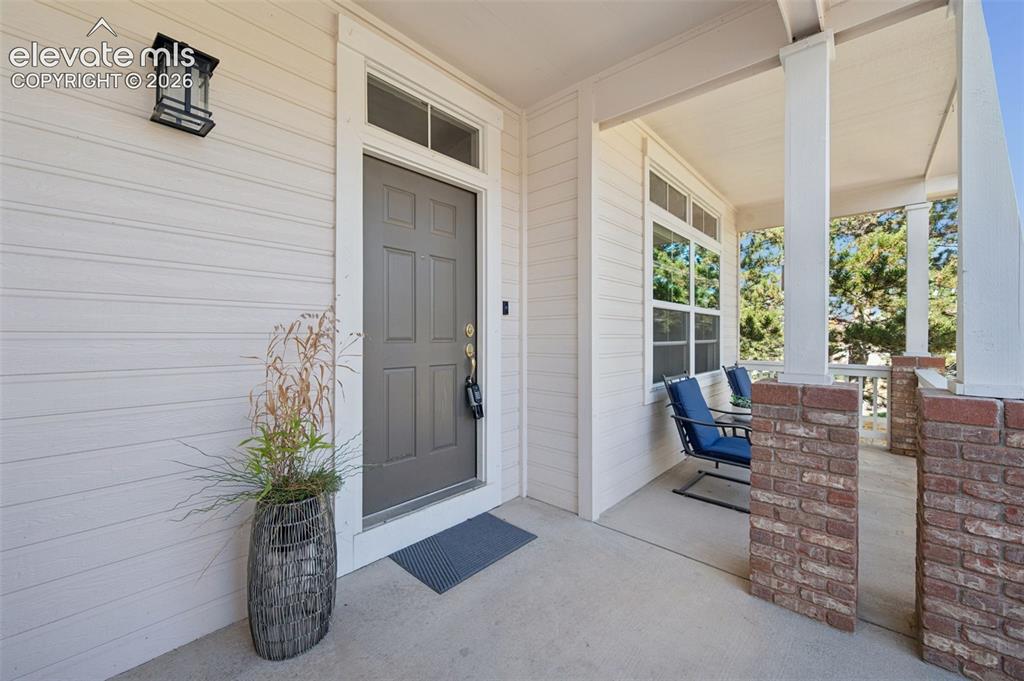 Image 4 of 37: Covered front porch featuring a concrete floor, exterior wall-mounted light