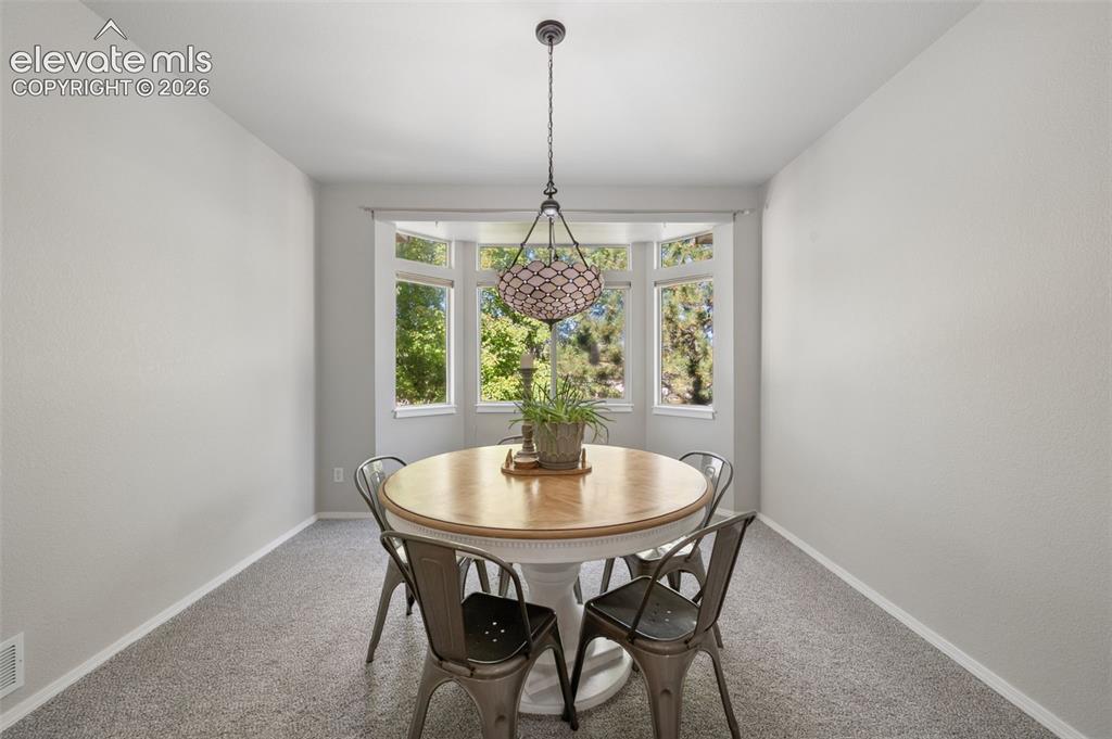 Image 8 of 37: Dining area featuring a bay window, neutral wall paint, carpeted flooring,