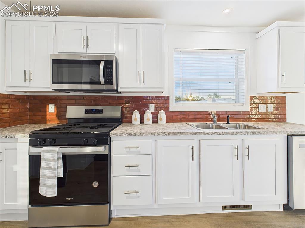 Image 17 of 50: A closer look at the kitchen reveals a Whirlpool gas range, built-in microw