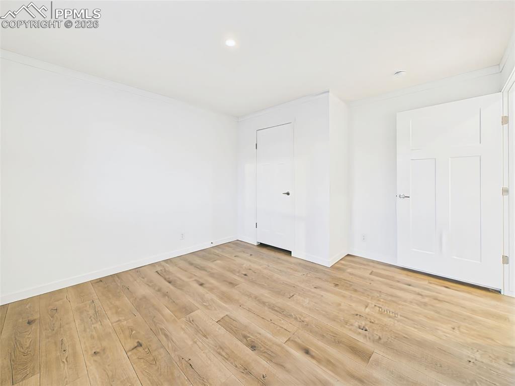 Image 32 of 50: Blank canvas bedroom 2 with wood-look flooring and generous closet space.