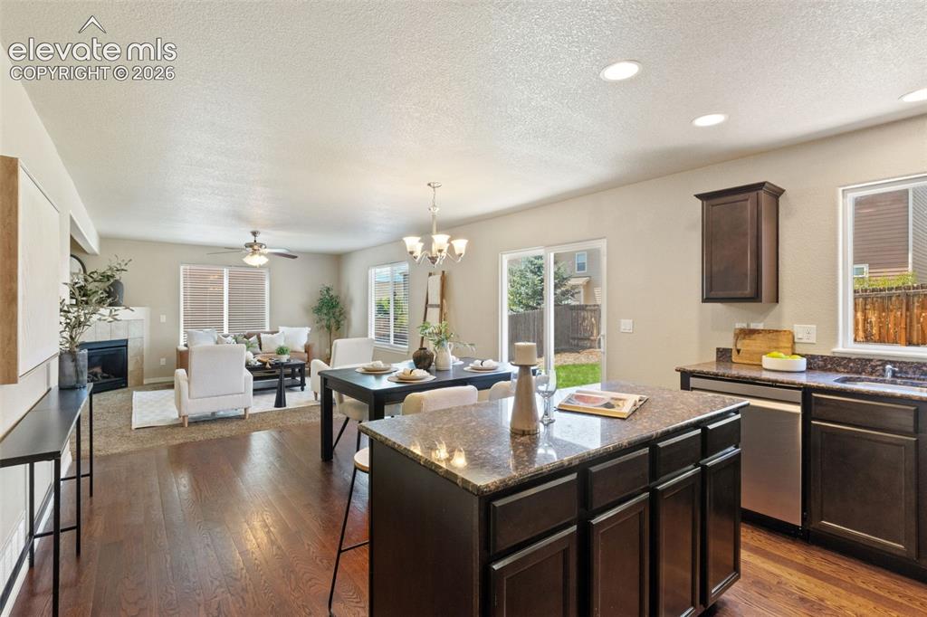 Image 10 of 35: Open-concept living area featuring rich wood-finish flooring, a kitchen isl