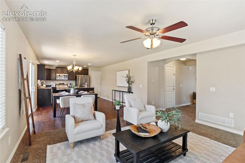 Image 14 of 35: Open-concept living space featuring a ceiling fan, carpet flooring, and an