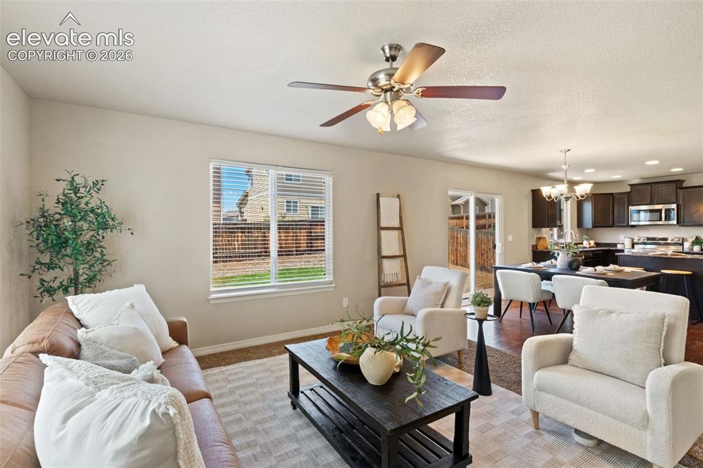 Image 16 of 35: Open-concept living space featuring a ceiling fan with integrated lighting,