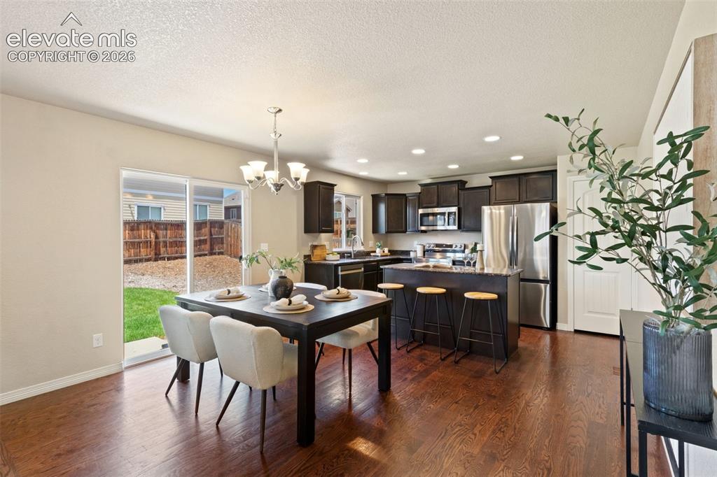 Image 3 of 35: Open-concept kitchen and dining area featuring rich wood-finish flooring, d