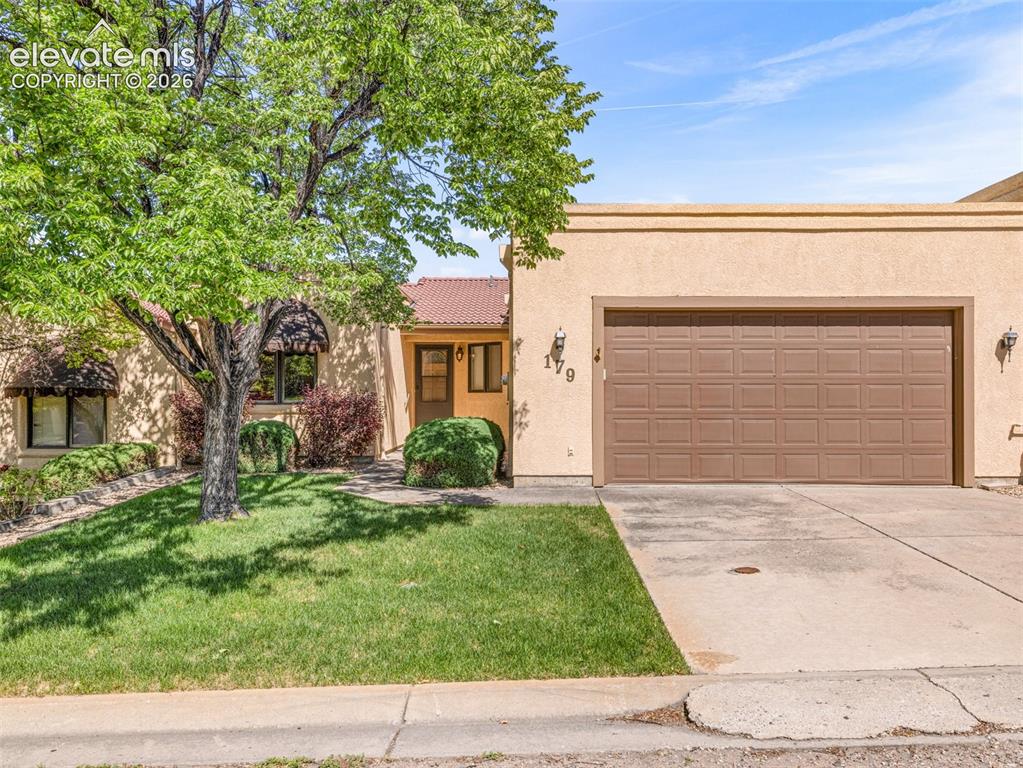 Image 1 of 24: Stucco exterior with an attached garage, a tile roof section, mature tree,