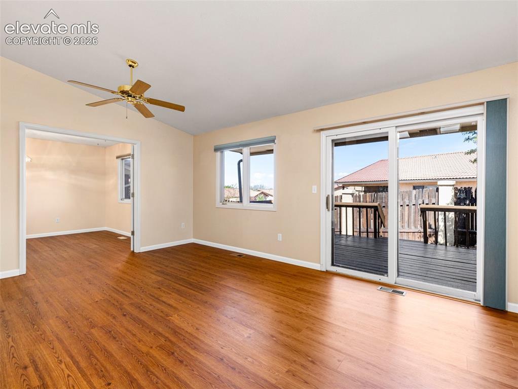 Image 10 of 24: Spacious room with wood-finish flooring, a ceiling fan, and sliding glass d