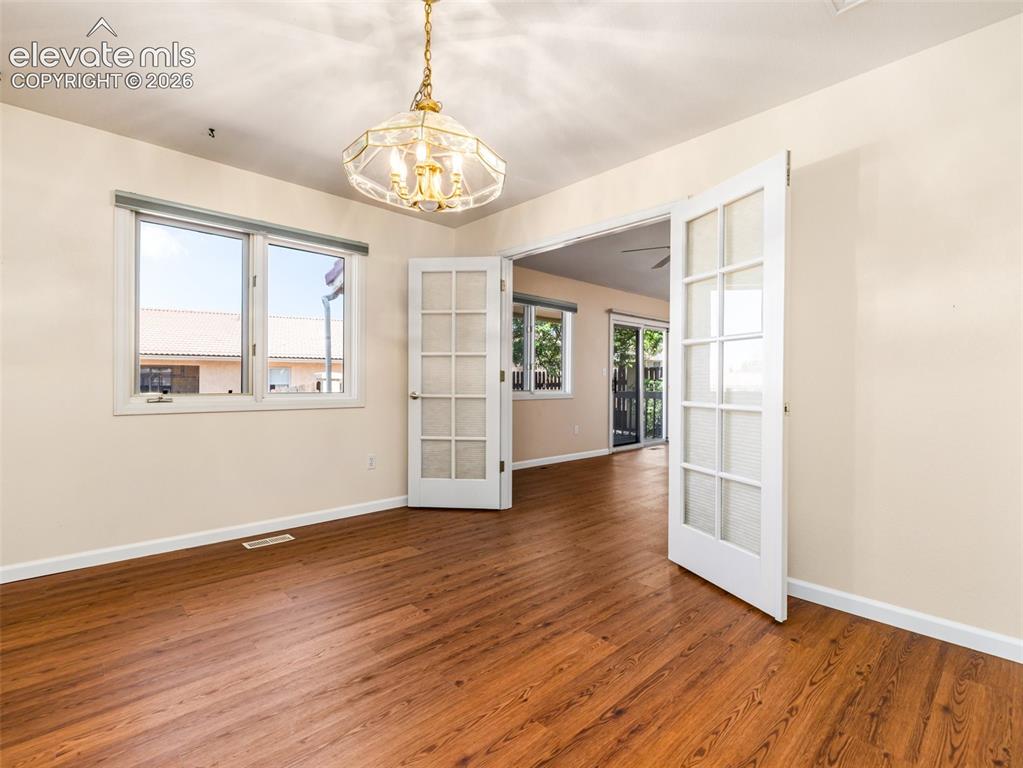 Image 15 of 24: Spacious room featuring wood-finish flooring, a decorative brass chandelier
