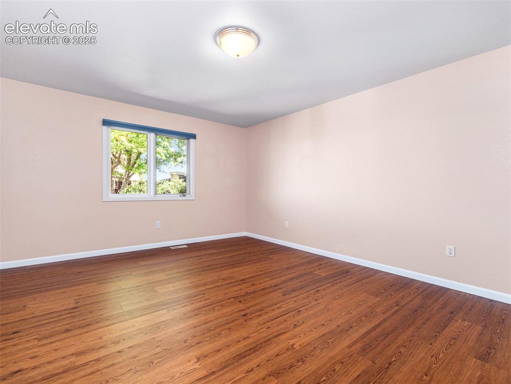 Image 16 of 24: Spacious interior room featuring wood-finish flooring, a white trim window,