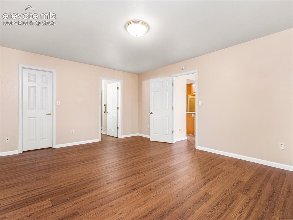 Image 17 of 24: Spacious room featuring wood-finish flooring, light-toned walls, and multip