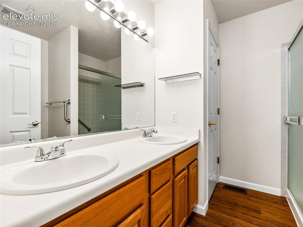 Image 19 of 24: Bathroom featuring a dual-sink vanity with wood cabinetry, a large wall-mou