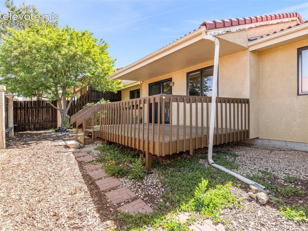 Image 22 of 24: Outdoor wood-finish deck with railing and steps, complemented by a stucco e