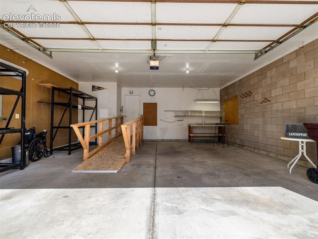 Image 23 of 24: Spacious garage with concrete flooring, exposed block wall, and integrated