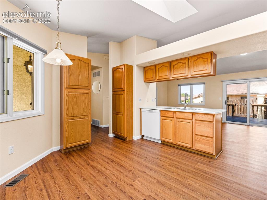 Image 9 of 24: Kitchen area featuring wood-finish flooring, light wood cabinetry, white co