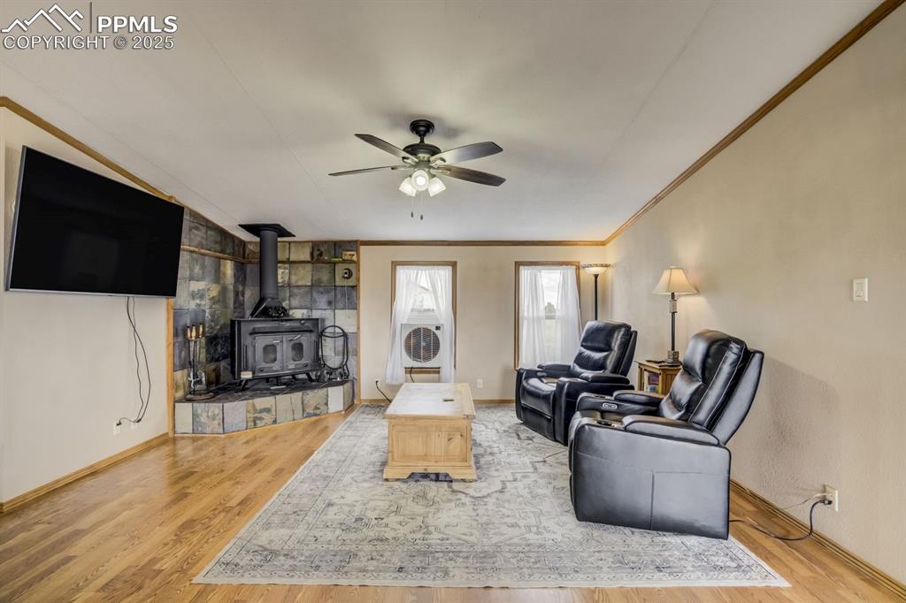 Image 10 of 43: Living room with a wood stove, light wood-type flooring, ornamental molding