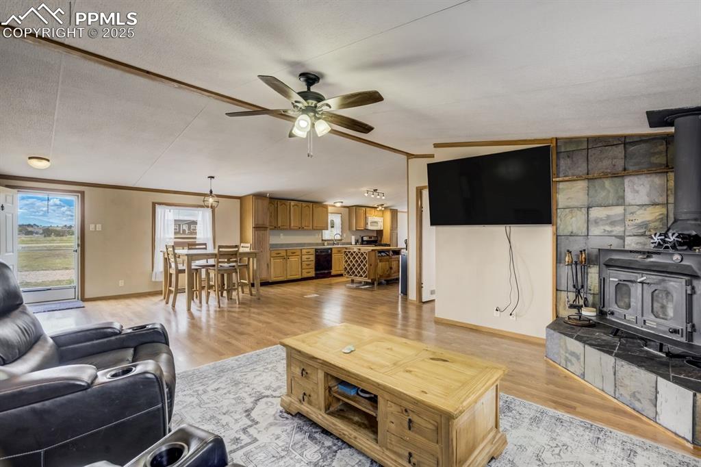 Image 11 of 43: Living area with a wood stove, light wood-style flooring, vaulted ceiling, 