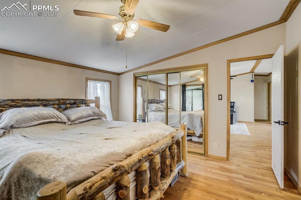 Image 19 of 43: Bedroom with crown molding, lofted ceiling, light wood finished floors, cei