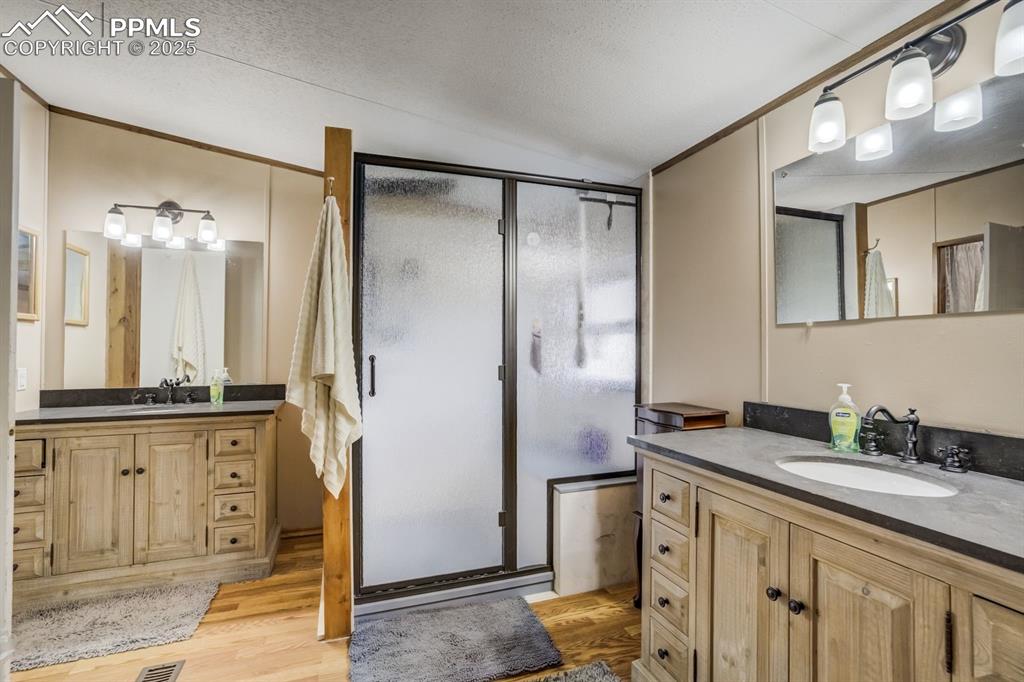 Image 20 of 43: Full bath featuring a shower stall, two vanities, light wood-style flooring
