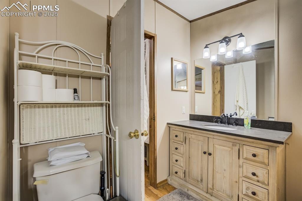 Image 21 of 43: Half bath featuring vanity, light wood finished floors, and ornamental mold