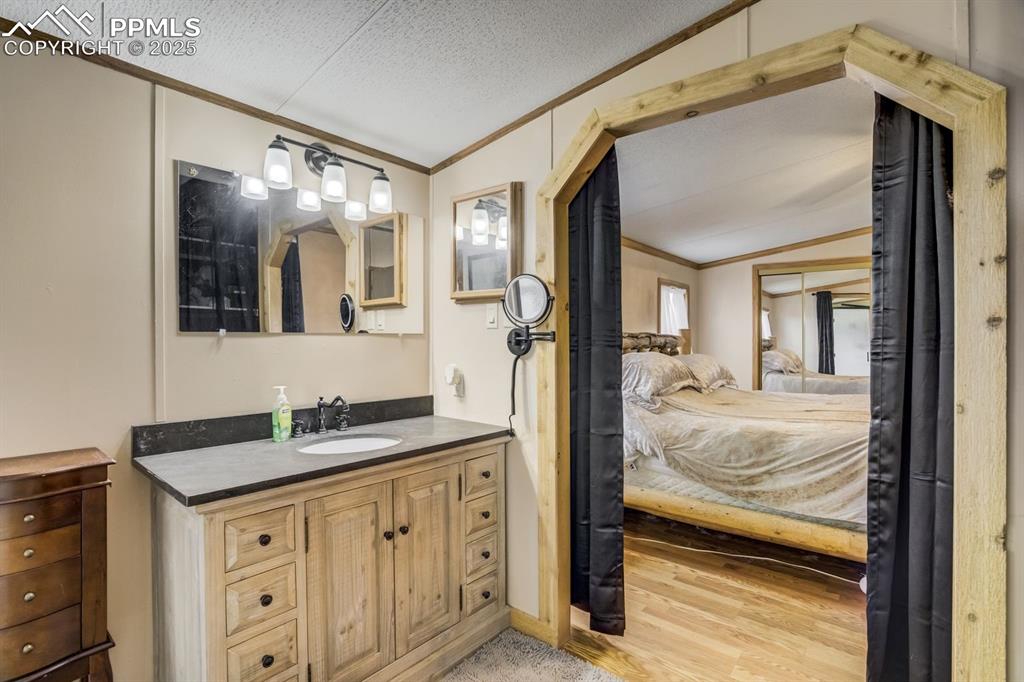 Image 23 of 43: Bathroom featuring ensuite bathroom, crown molding, vanity, a textured ceil