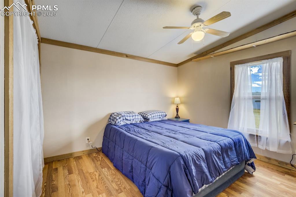 Image 25 of 43: Bedroom featuring wood finished floors, vaulted ceiling, a ceiling fan, and