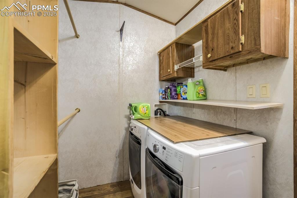 Image 27 of 43: Laundry area with washer and clothes dryer, cabinet space, and dark wood-st