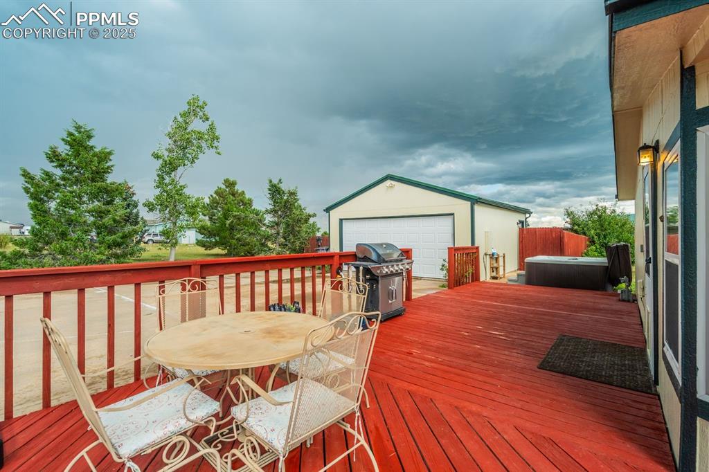 Image 28 of 43: Wooden deck with an outbuilding, a detached garage, area for grilling, and 