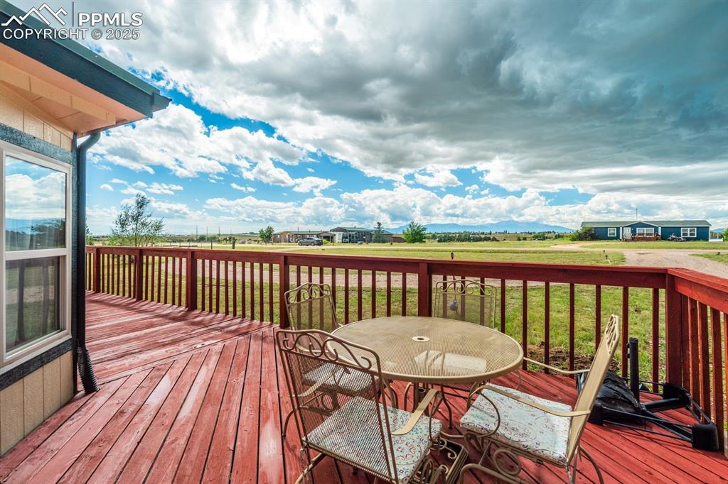 Image 29 of 43: Wooden deck featuring a lawn and outdoor dining area