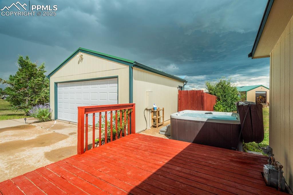Image 30 of 43: Wooden deck with an outbuilding, a garage, and a hot tub