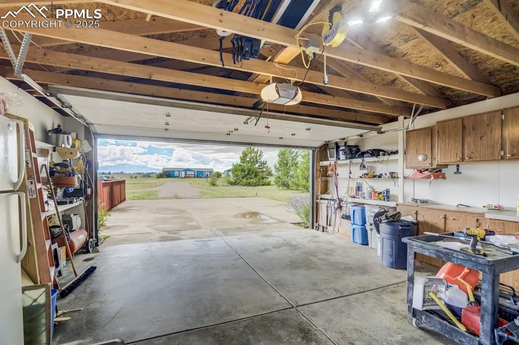 Image 33 of 43: Garage with freestanding refrigerator, a garage door opener, and a workshop