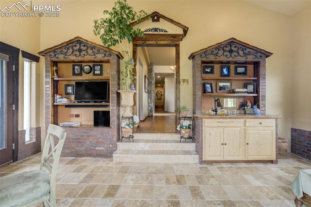 Image 21 of 50: The sun room has been thoughtfully finished with built-ins and a small wet-
