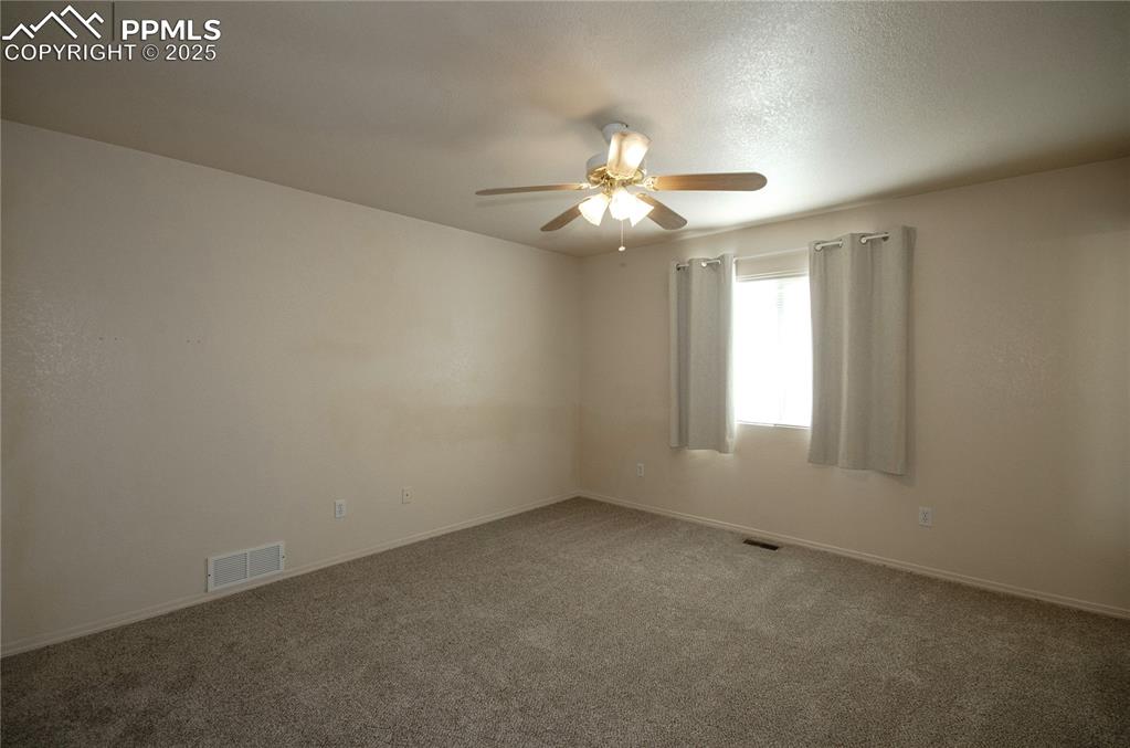 Image 12 of 25: Primary or Master bedroom featuring new carpet flooring and ceiling fan