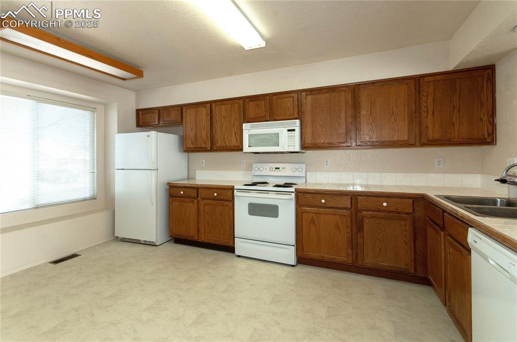 Image 2 of 25: Spacious kitchen with built-in microwave tile countertops