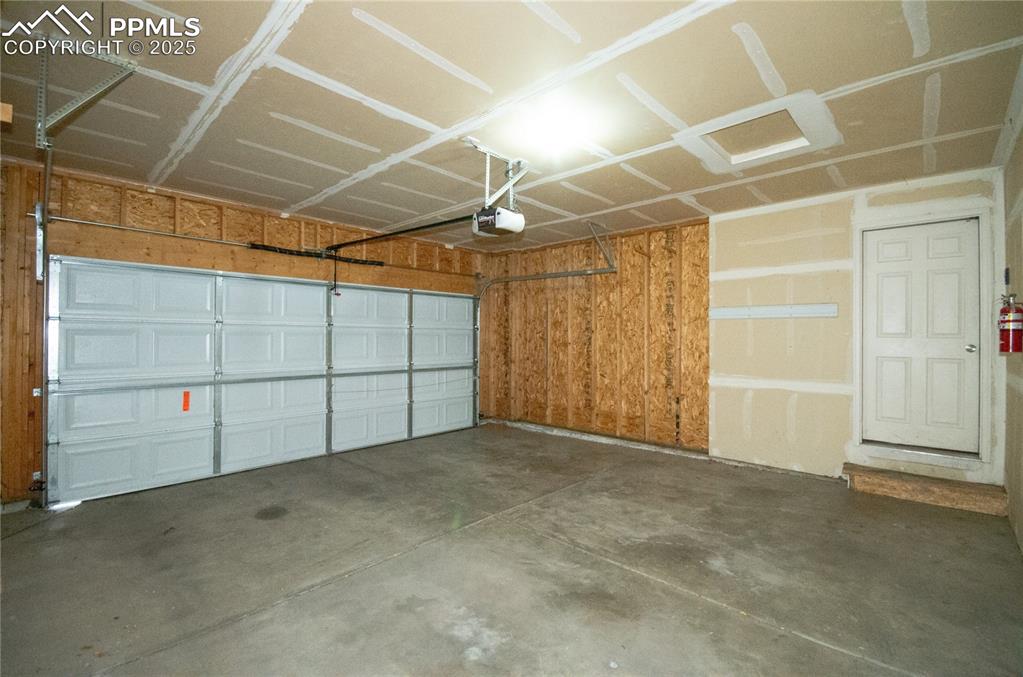 Image 22 of 25: Spacious 2-car Garage featuring a garage door opener