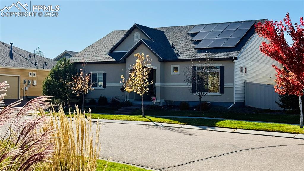 Image 2 of 28: View of front facade with solar panels, stucco siding, and a shingled roof