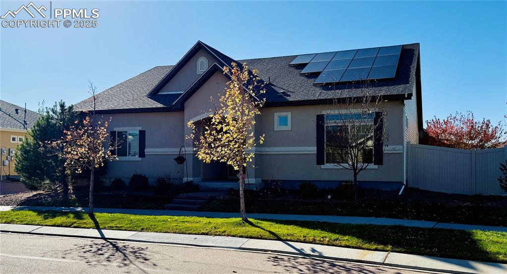 Image 4 of 28: View of front of home with roof mounted solar panels, roof with shingles, a