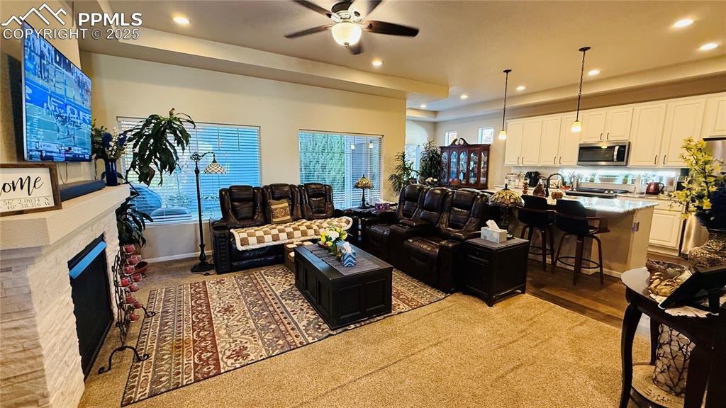 Image 7 of 28: Living area featuring a raised ceiling, ceiling fan, recessed lighting, a f