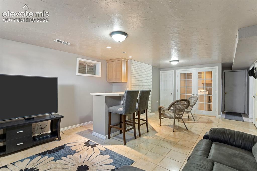 Image 18 of 24: Living room featuring french doors, a textured ceiling, and light tile floo