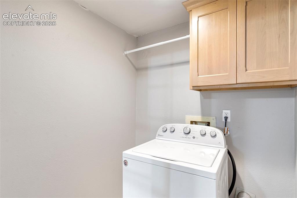 Image 19 of 24: Clothes washing area with cabinets and washer / dryer