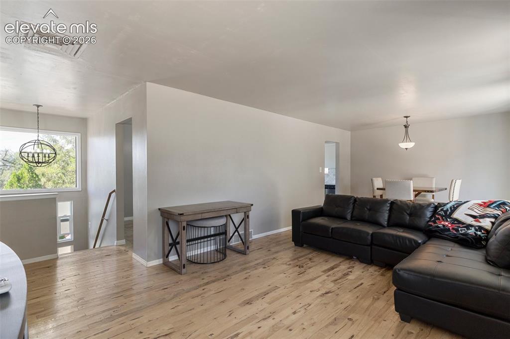 Image 4 of 24: Living room with a notable chandelier and wood-type flooring
