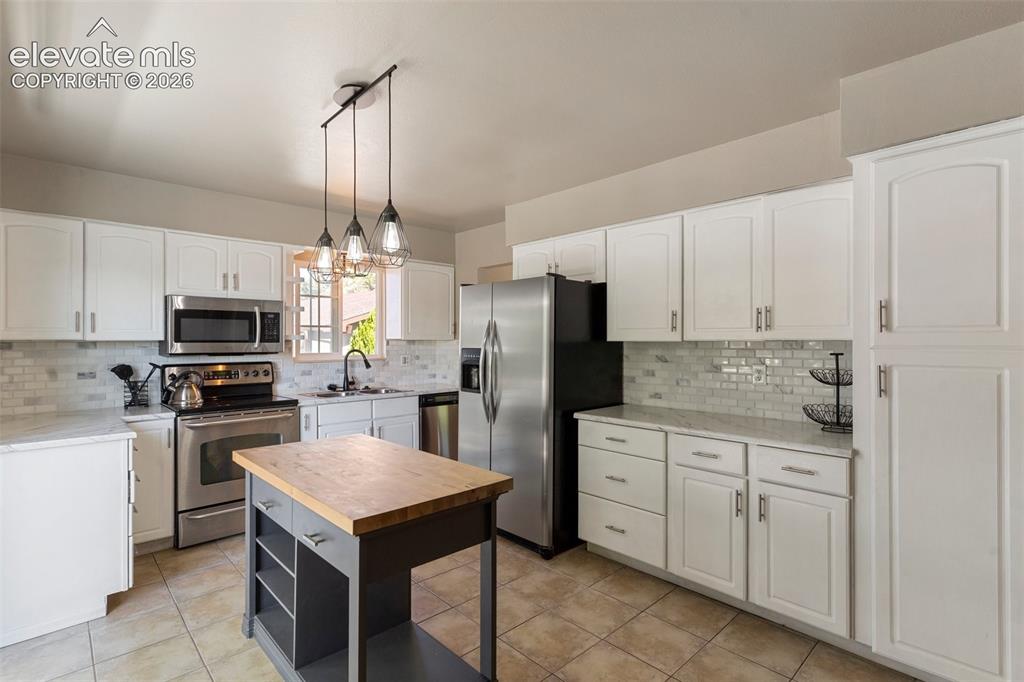 Image 5 of 24: Kitchen featuring stainless steel appliances, hanging light fixtures, taste