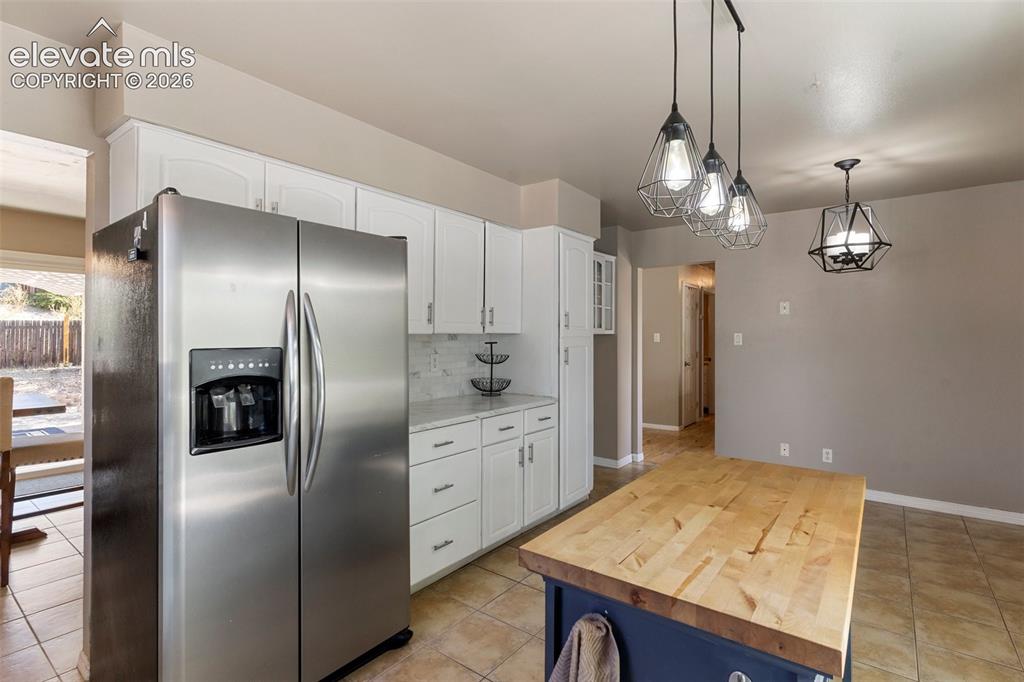 Image 6 of 24: Kitchen with white cabinets, wooden counters, backsplash, stainless steel r