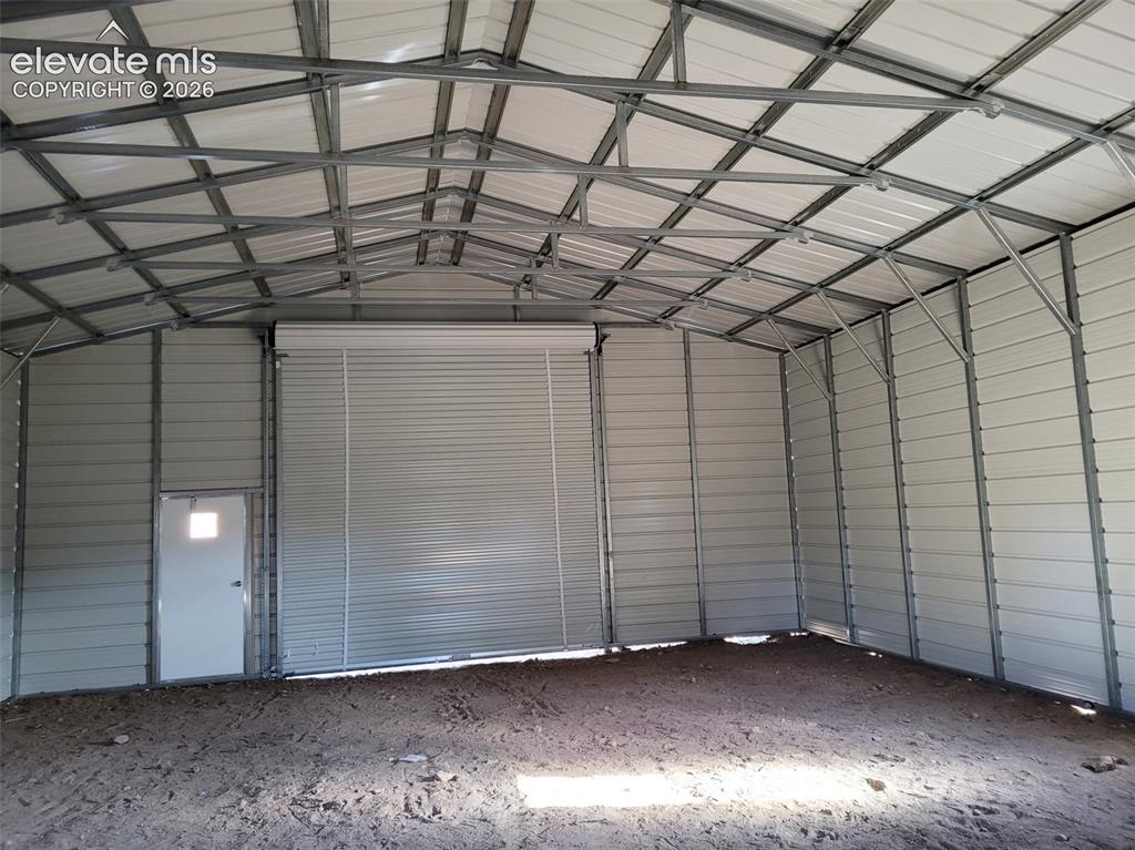 Image 20 of 33: Metal frame structure with corrugated metal siding, featuring a roll-up doo