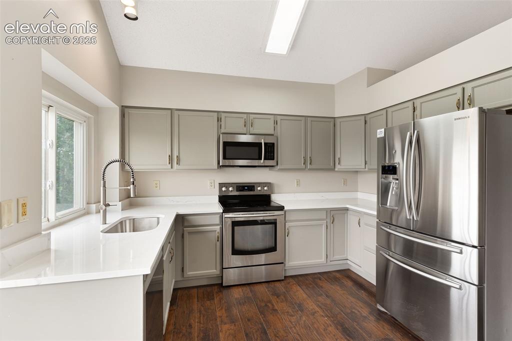 Image 11 of 38: Kitchen featuring stainless steel appliances, light gray cabinetry, white c